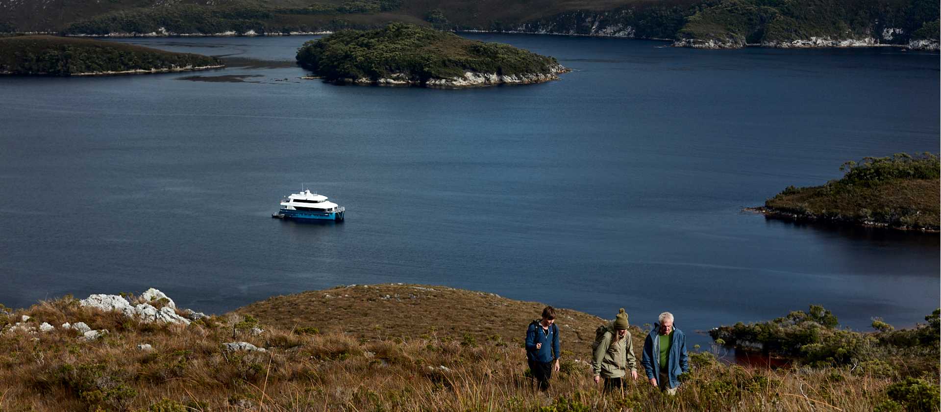 Guests on hike to Mt Stokes, Odalisque III in the entrance to Bathurst Channel | Tim Grey